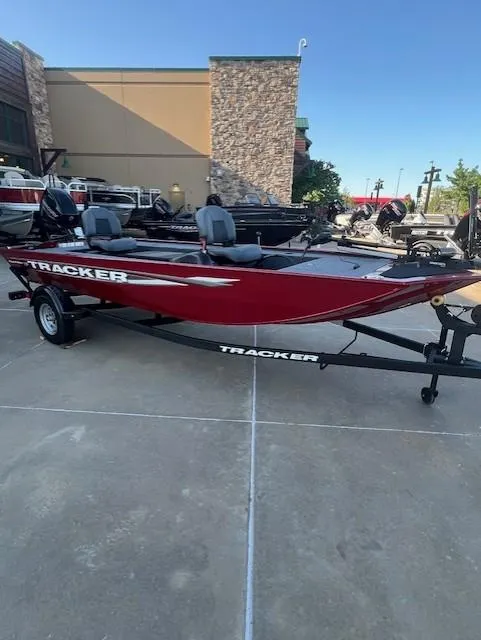 The Image of 2025 Tracker Panfish 17 boat in red, parked on a trailer outside a building. - 0