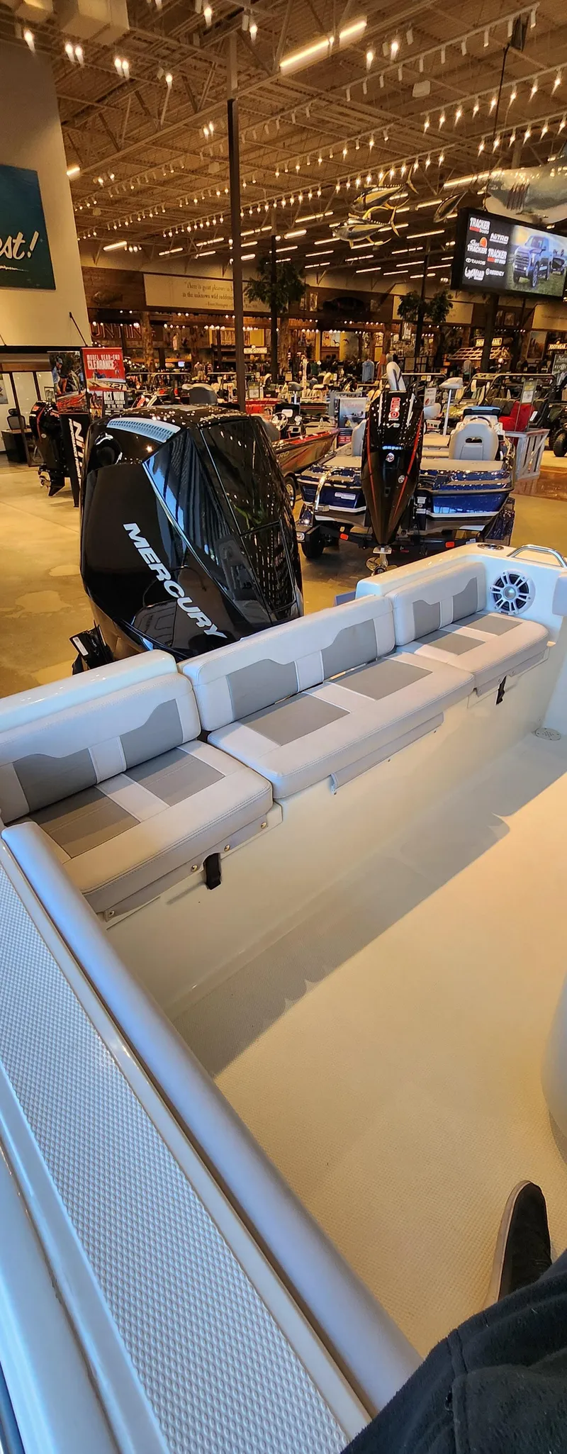 Slide: The Image of 2025 Mako 214 CC boat interior at a showroom, featuring seating and engine display. - 6