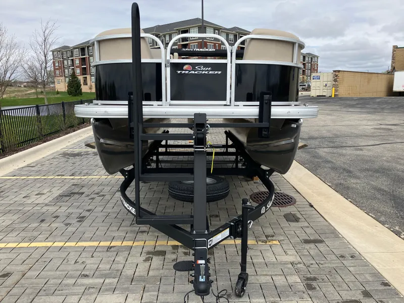 Slide: The Image of 2025 Sun Tracker Party Barge 16 DLX pontoon boat on trailer in parking lot. - 2