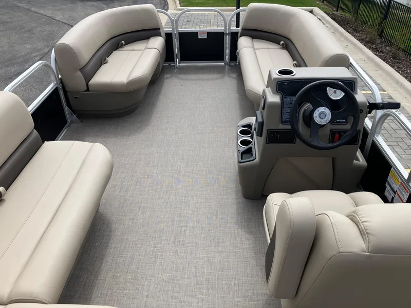 Slide: The Image of 2025 Sun Tracker Party Barge 16 DLX interior with beige seating and steering console. - 6