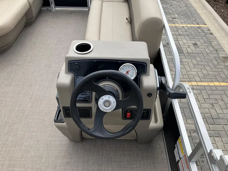 Slide: The Image of 2025 Sun Tracker Party Barge 16 DLX steering console with beige seating and cup holder. - 7