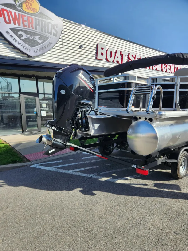 Slide: The Image of 2025 Sun Tracker SportFish 20 DLX pontoon boat at dealership, featuring powerful outboard motor. - 2