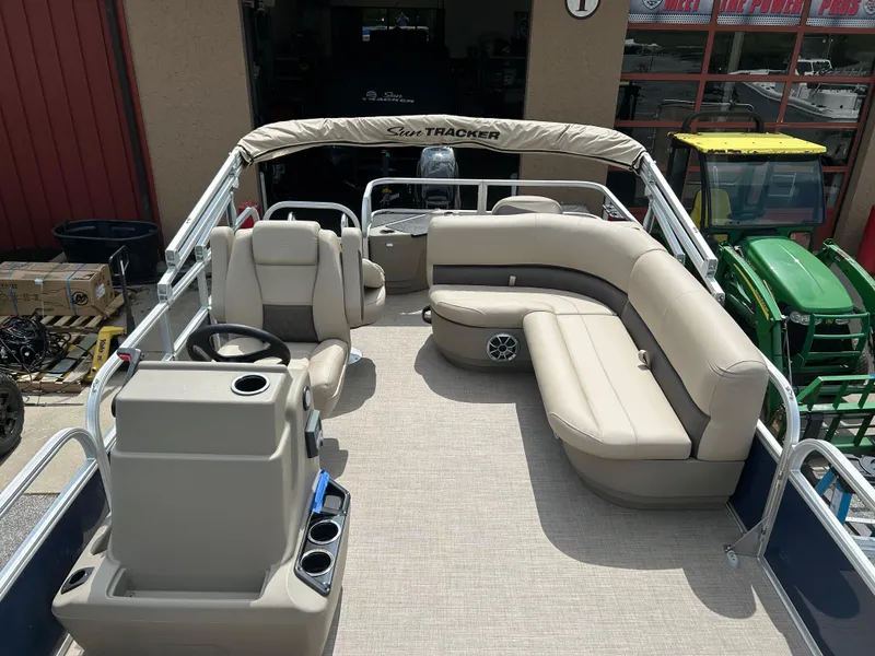 Slide: The Image of 2025 Sun Tracker Bass Buggy 18 DLX pontoon boat with beige seating and steering console. - 3