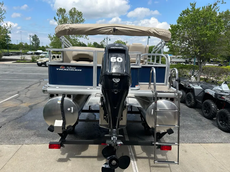 Slide: The Image of 2025 Sun Tracker Bass Buggy 18 DLX pontoon boat with 60 HP Mercury engine, parked outdoors. - 4