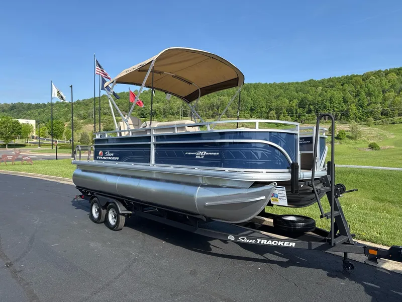 Slide: The Image of 2025 Sun Tracker Fishin' Barge 20 DLX pontoon boat on trailer, scenic background. - 3