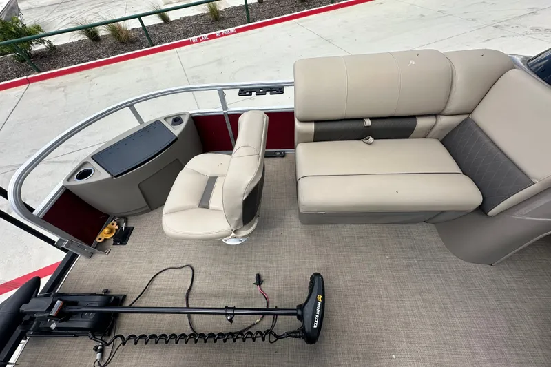 Slide: The Image of 2024 Regency 230 LE3 pontoon boat interior with beige seating and trolling motor. - 11