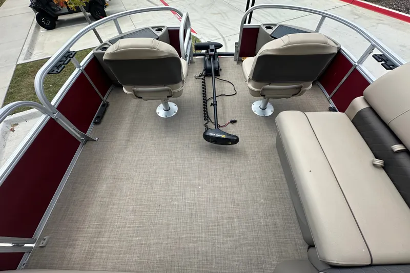 Slide: The Image of 2024 Regency 230 LE3 pontoon boat interior with beige seating and red side panels. - 8