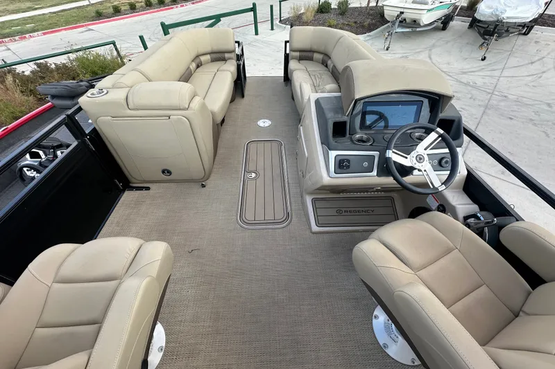 Slide: The Image of 2024 Regency 230 LE3 pontoon boat interior with beige seating and modern dashboard. - 17