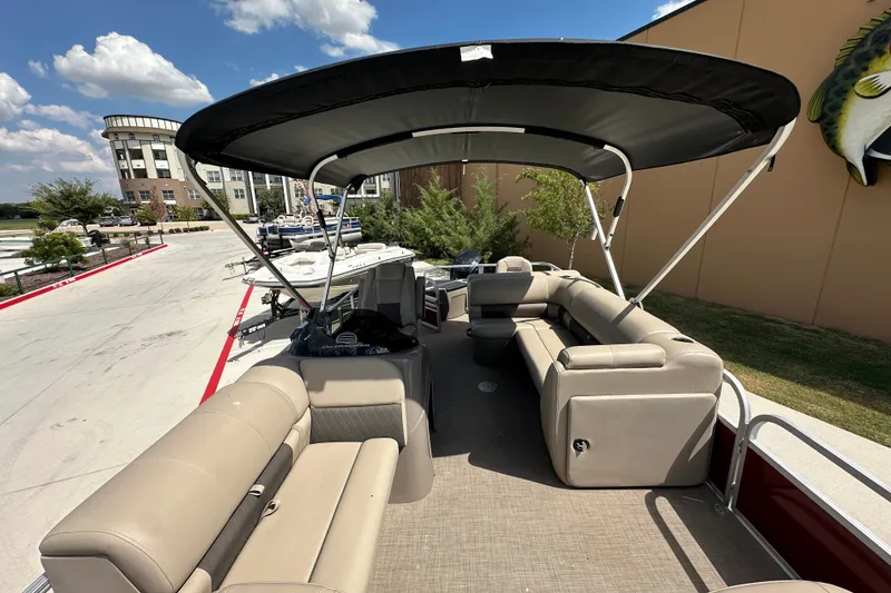Slide: The Image of 2024 Regency 230 LE3 pontoon boat with canopy, beige seating, and spacious deck. - 3