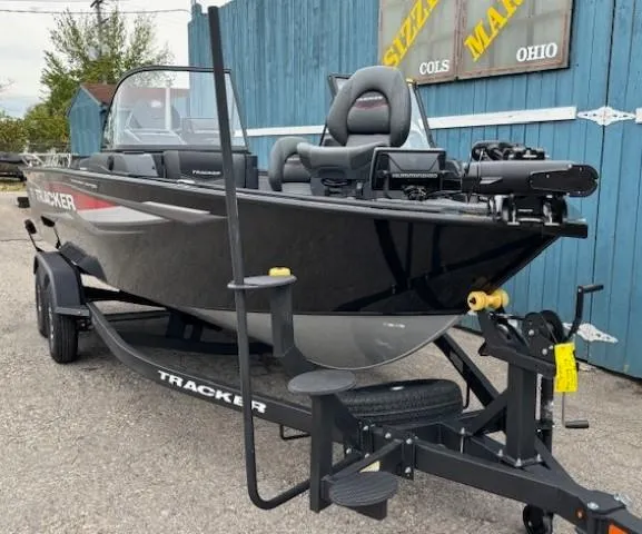 Slide: The Image of 2025 Tracker Targa V-19 Combo boat on trailer, parked outdoors near blue building. - 2