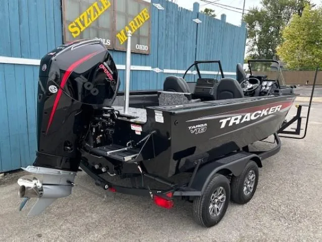 Slide: The Image of 2025 Tracker Targa V-19 Combo boat with outboard motor, parked near blue building. - 3