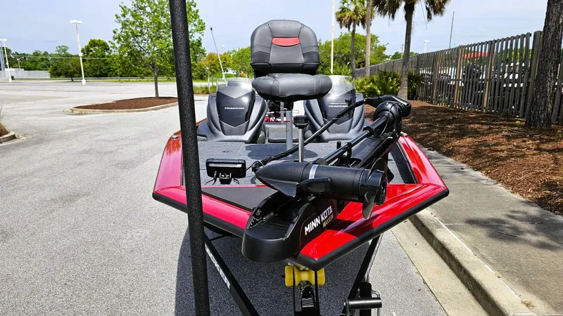 Slide: The Image of 2025 Tracker Pro Team 175 boat with red trim and fishing seats in a parking lot. - 9