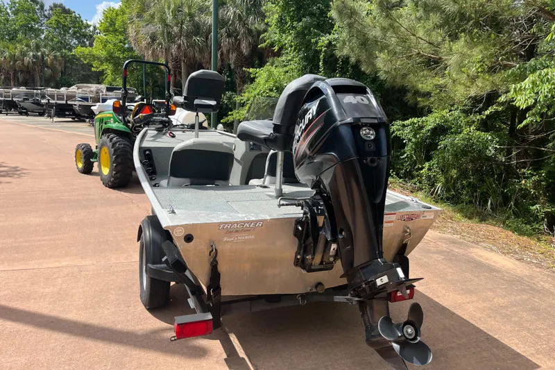 Slide: The Image of 2017 Tracker PRO160 boat with outboard motor, parked on a sunny day near trees. - 2