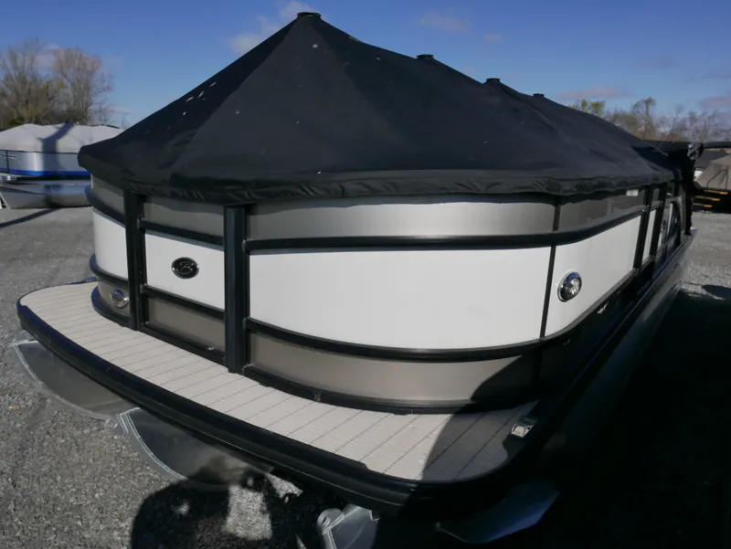Slide: The Image of 2019 Barletta L23QCSS pontoon boat with black cover, parked outdoors. - 2