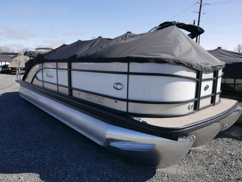 Slide: The Image of 2019 Barletta L23QCSS pontoon boat with cover, parked on gravel. - 3