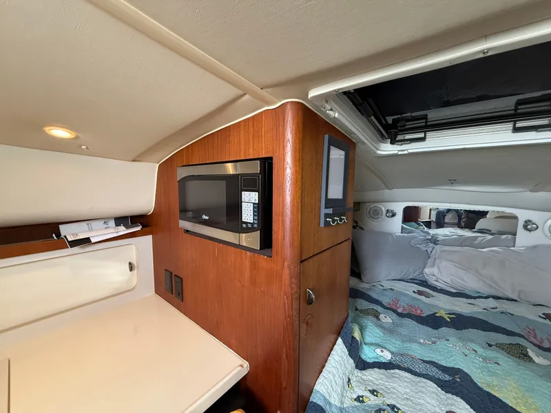 Slide: The Image of 1998 Tiara Yachts 2900 Open cabin interior with microwave and cozy bedding. - 22