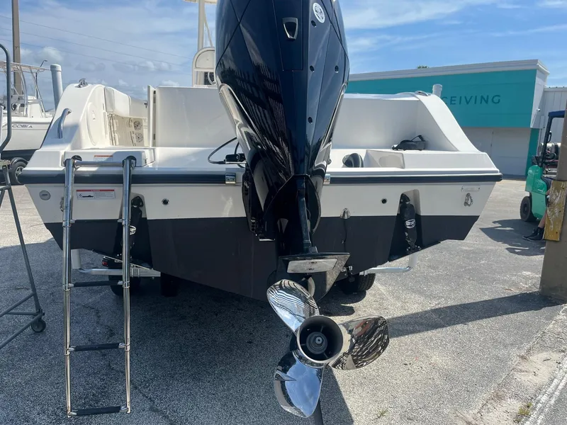 Slide: The Image of 2022 Cobia 237 Center Console boat with outboard motor and ladder, parked on concrete. - 5