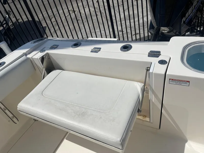 Slide: The Image of 2022 Cobia 237 Center Console boat with foldable white seat and rod holders. - 8
