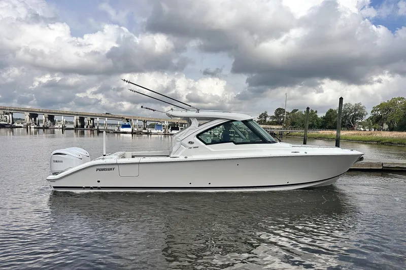 The Image of 2025 Pursuit DC 326 Dual Console boat on a calm river under cloudy skies. - 0