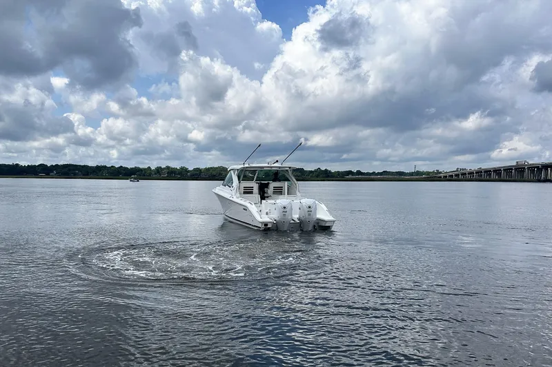 Slide: The Image of 2025 Pursuit DC 326 Dual Console boat on a calm lake under cloudy skies. - 10