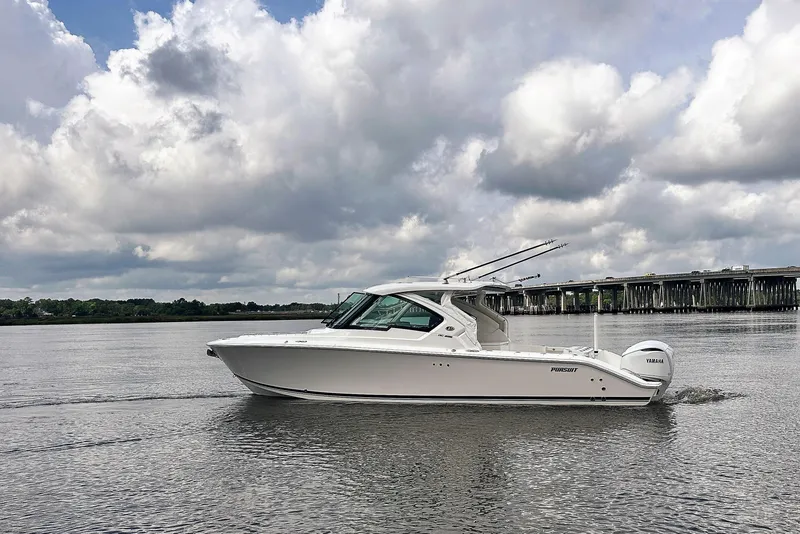 Slide: The Image of 2025 Pursuit DC 326 Dual Console boat cruising on a calm river under cloudy skies. - 8