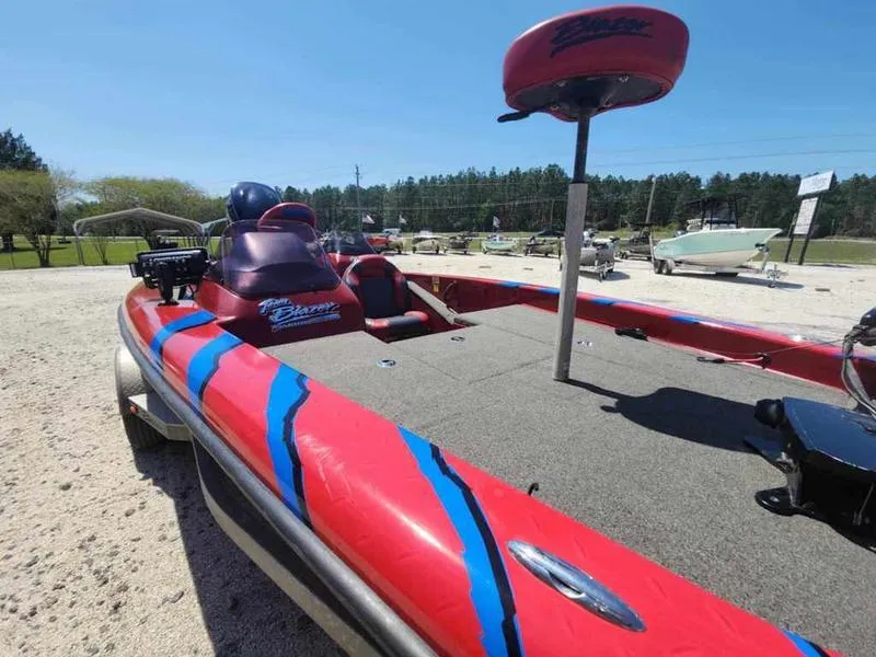 Slide: The Image of 2007 Blazer 190 Pro-V boat with red and blue design, parked outdoors. - 12