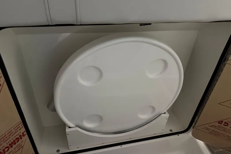 Slide: The Image of 2025 Sea Ray Sundancer 320 storage compartment with a round white cover. - 30