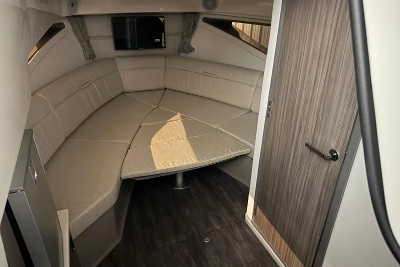 Slide: The Image of 2025 Sea Ray Sundancer 320 cabin interior with beige seating and wood accents. - 45