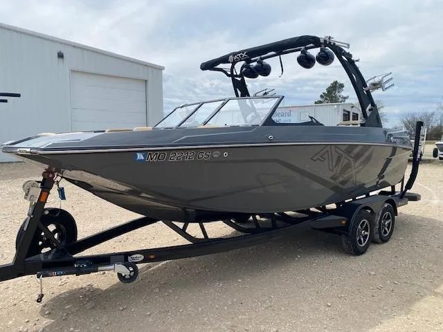 Slide: The Image of 2022 ATX Surf Boats 22 Type-S on trailer, parked outdoors near a warehouse. - 2