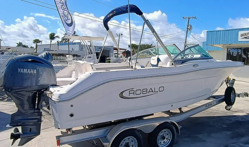 Slide: The Image of 2024 Robalo R207 Dual Console boat on trailer with Yamaha engine, outdoor display. - 1