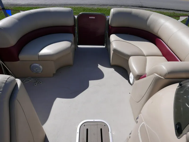 Slide: The Image of 2015 Manitou Oasis boat interior with beige and maroon seating, spacious layout. - 11