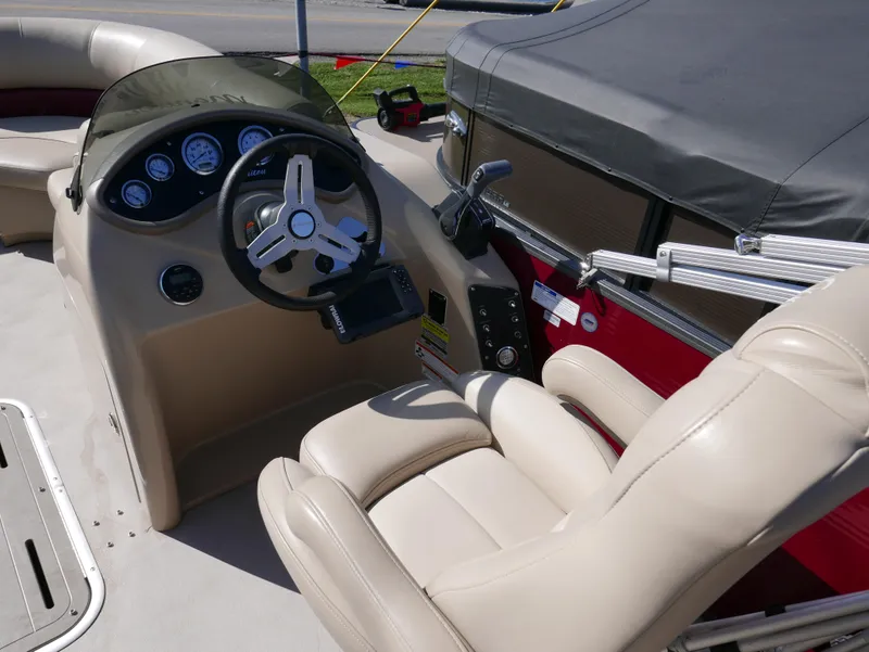 Slide: The Image of 2015 Manitou Oasis boat interior with steering wheel and dashboard controls. - 14