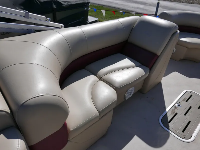 Slide: The Image of 2015 Manitou Oasis boat seating with beige and maroon upholstery, featuring comfortable cushions. - 16