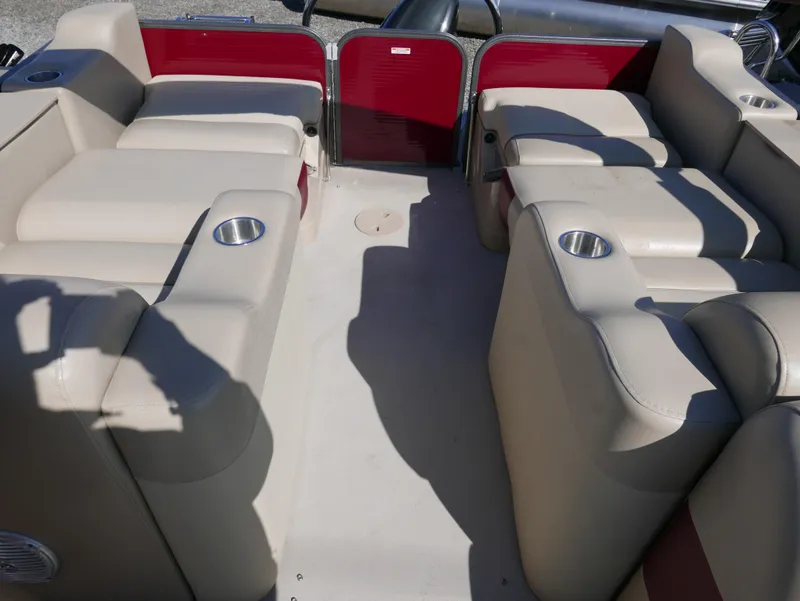 Slide: The Image of 2015 Manitou Oasis boat interior with beige seating and cup holders. - 17