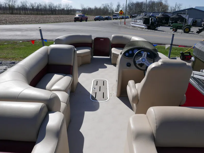 Slide: The Image of 2015 Manitou Oasis pontoon boat interior with beige seating and steering console. - 19