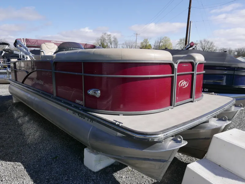 Slide: The Image of 2015 Manitou Oasis pontoon boat with red exterior, parked on gravel. - 7