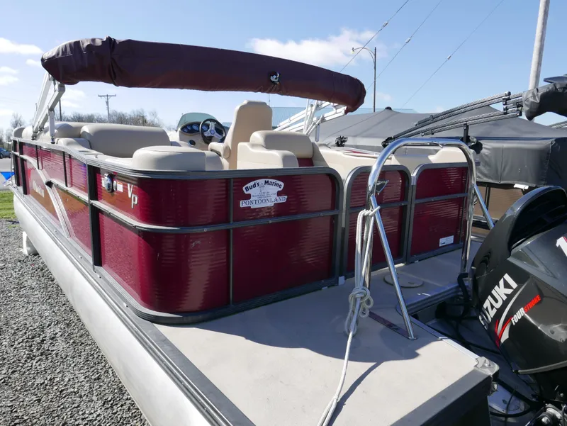 Slide: The Image of 2015 Manitou Oasis pontoon boat with Suzuki engine, parked on gravel. - 8