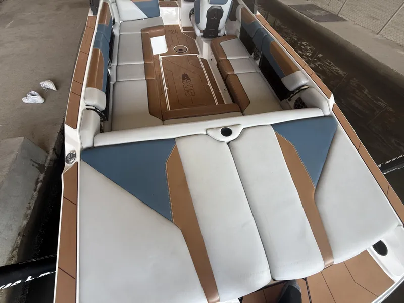 Slide: The Image of 2021 Axis A24 boat interior with blue and brown seating, docked by the water. - 12
