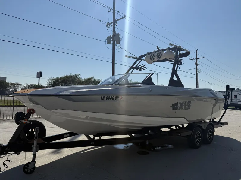 Slide: The Image of 2021 Axis A24 boat on trailer, parked outdoors under clear sky. - 2