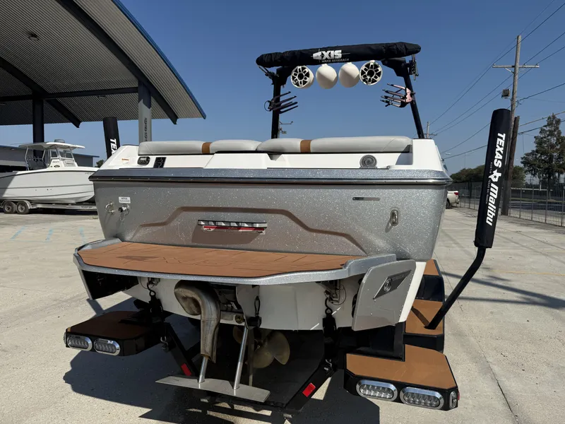 Slide: The Image of 2021 Axis A24 boat rear view with speakers and swim platform in a marina setting. - 4