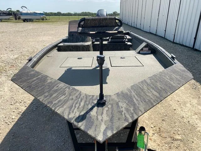 Slide: The Image of 2025 SeaArk Shadow 18 boat with camouflage design, parked outdoors near a building. - 2