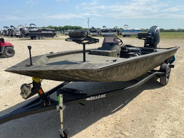 Slide: The Image of 2025 SeaArk Shadow 18 boat on trailer, parked outdoors, with motor and camouflage design. - 3