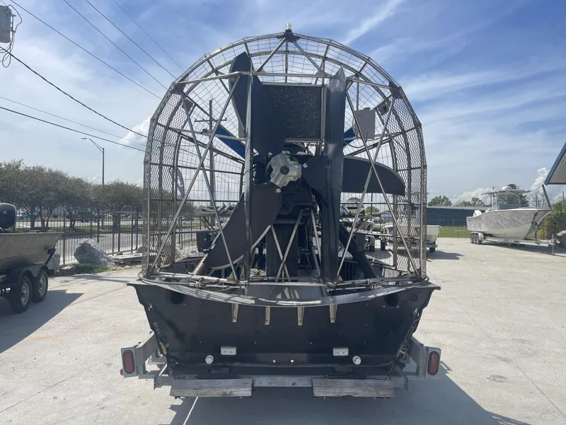 Slide: The Image of 2008 Custom Alumitech 20 Airboat with large propeller, parked outdoors under a clear sky. - 7