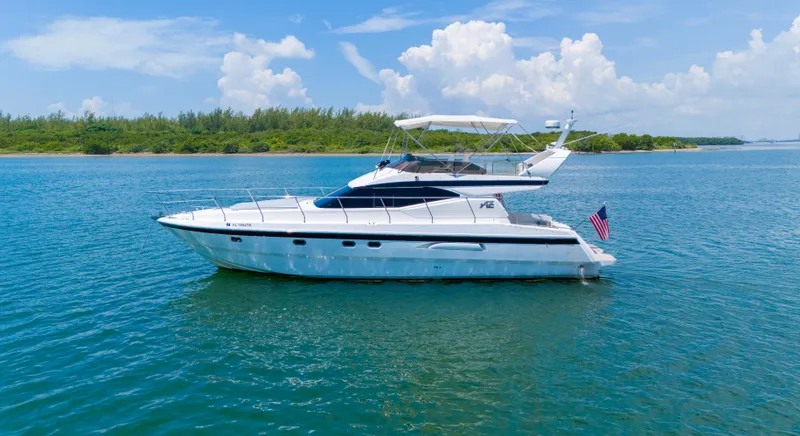 Slide: The Image of Azimut 43 Fly 1998 yacht on calm water, clear sky, and lush shoreline. - 1