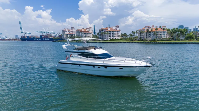 Slide: The Image of Azimut 43 Fly yacht from 1998 on calm waters with cityscape background. - 12