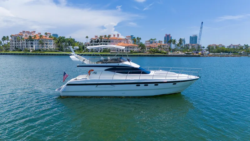 Slide: The Image of Azimut 43 Fly yacht from 1998 on calm water, with scenic coastal backdrop. - 7