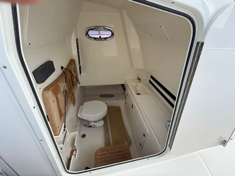 Slide: The Image of 2018 Boston Whaler 330 Outrage cabin interior with toilet and storage. - 11