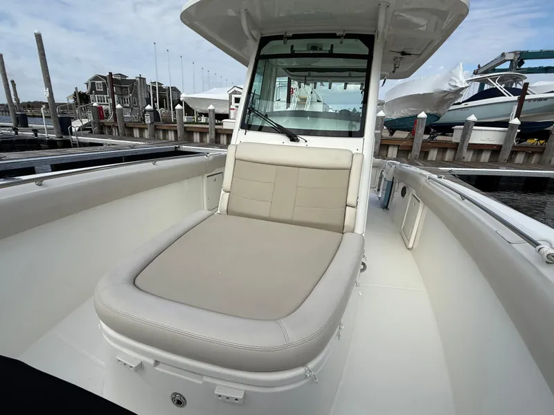 Slide: The Image of 2018 Boston Whaler 330 Outrage boat with cushioned seating at a marina. - 12