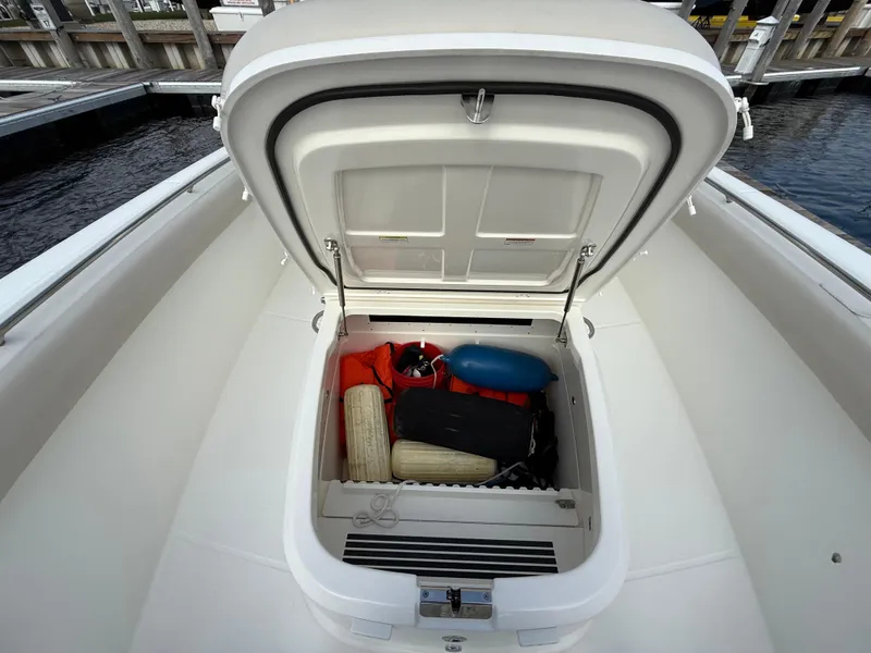 Slide: The Image of Open storage compartment on 2018 Boston Whaler 330 Outrage boat, containing safety equipment. - 13