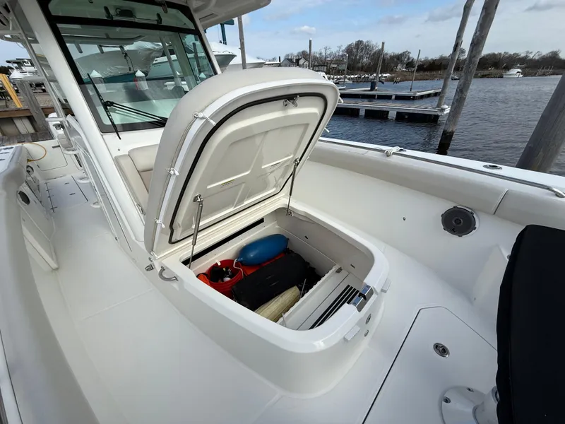 Slide: The Image of 2018 Boston Whaler 330 Outrage boat with open storage compartment at marina. - 14